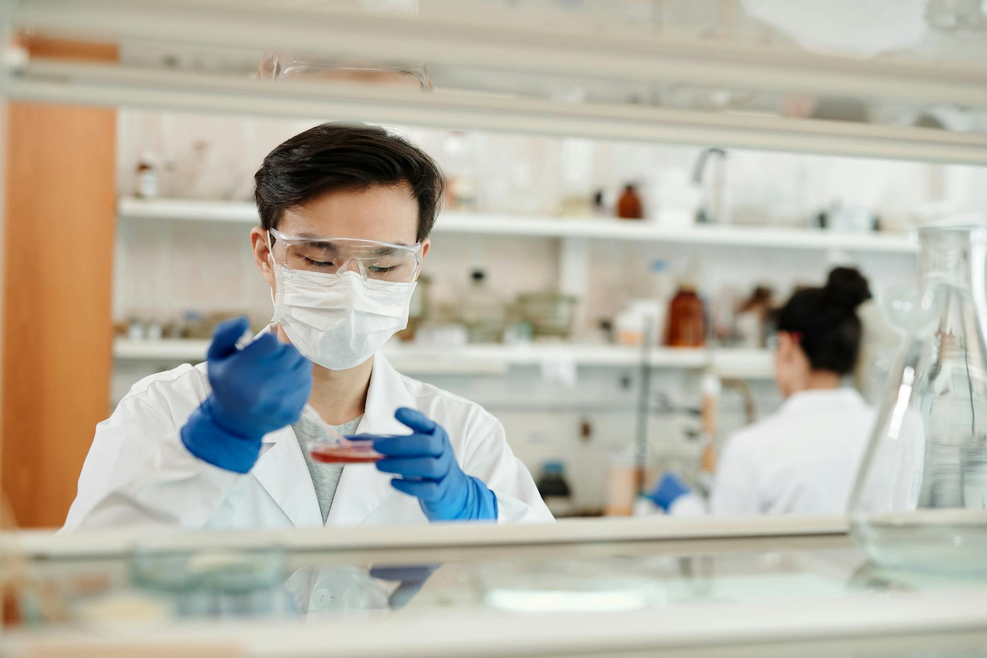 a photo of a medical professional drawing a sample from a petri dish