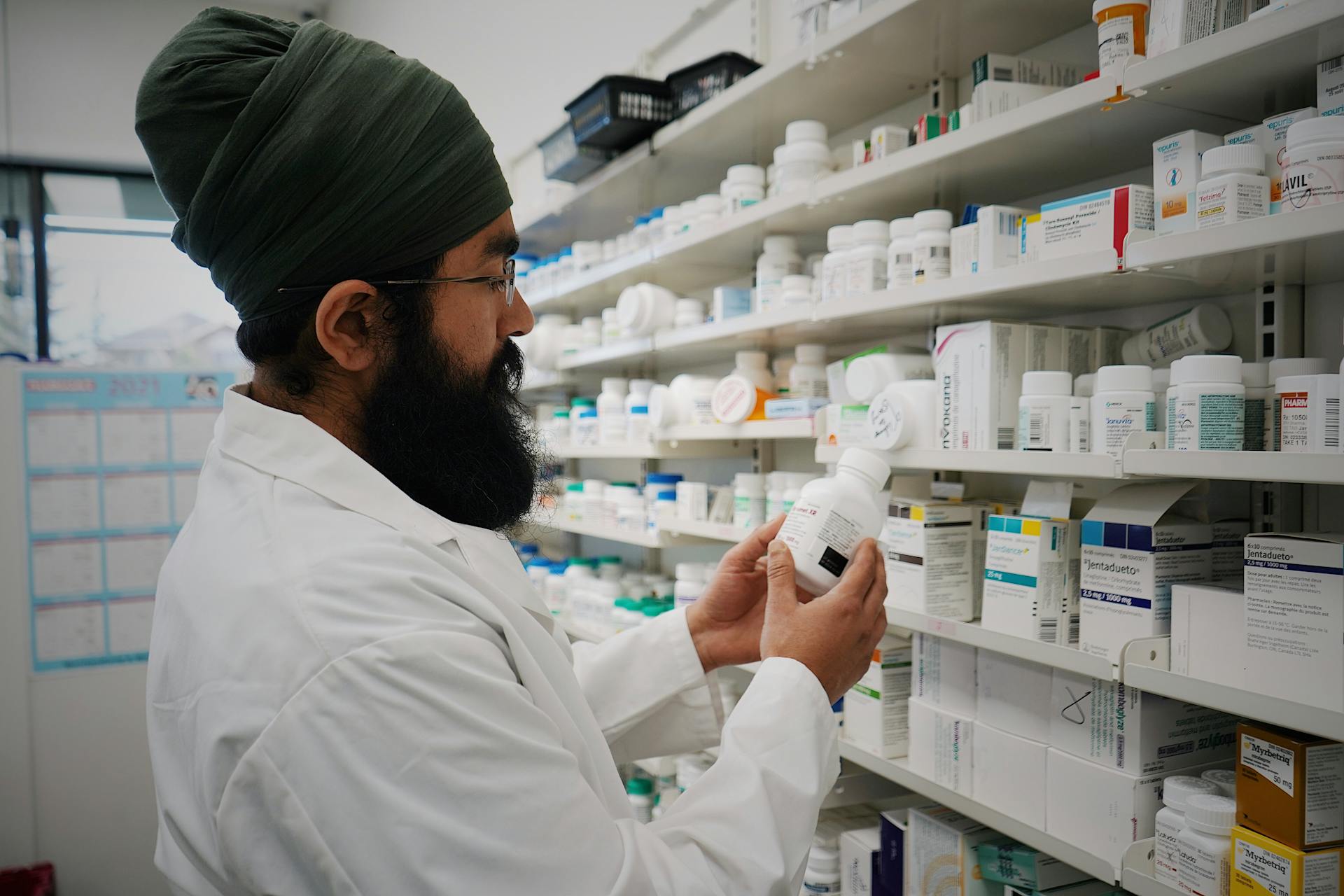 a photo of a pharmacist looking a medication while standing in front of a shelf of medications